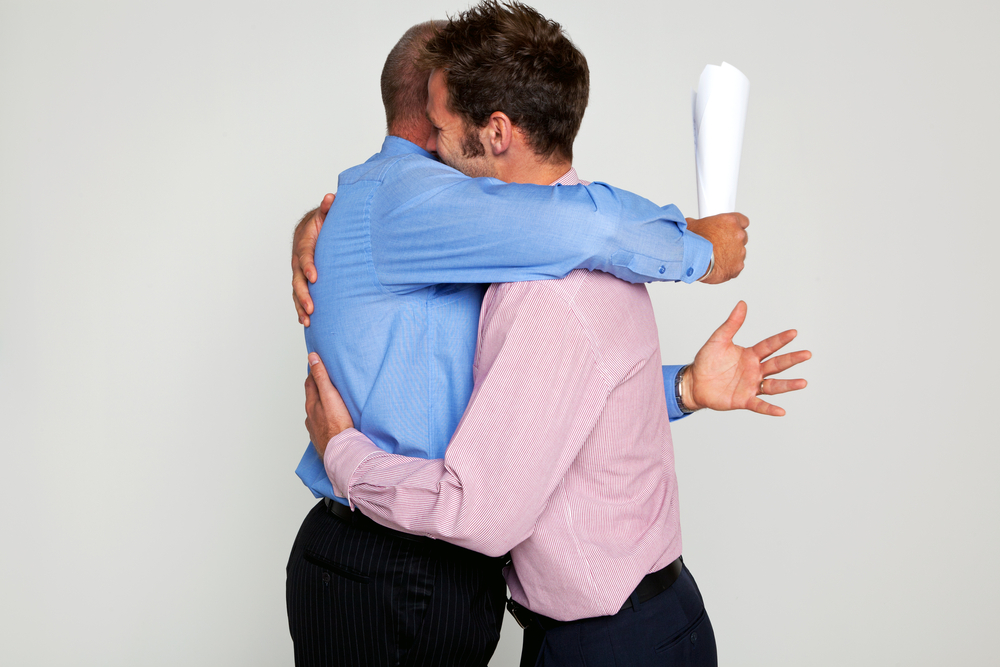 Photo,Of,Two,Businessmen,Hugging,Each,One,Holding,A,Contract,